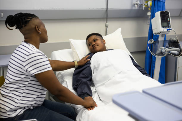 LGBTQIA woman with hand on partners shoulder giving support in hospital ward LGBTQIA woman with hand on partners shoulder giving support in hospital ward